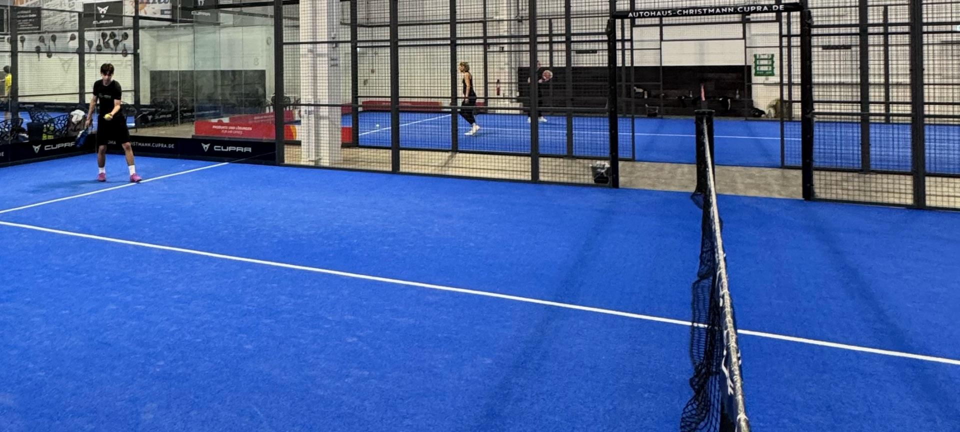 Indoor-Padel-Court: Spieler beim Training, Netz im Vordergrund